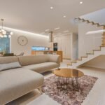 Contemporary living room with neutral tones, a sleek sofa, and elegant wooden staircase.