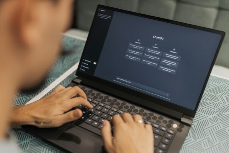 Close-up of a person typing on a laptop displaying the ChatGPT interface, emphasizing modern technology use.