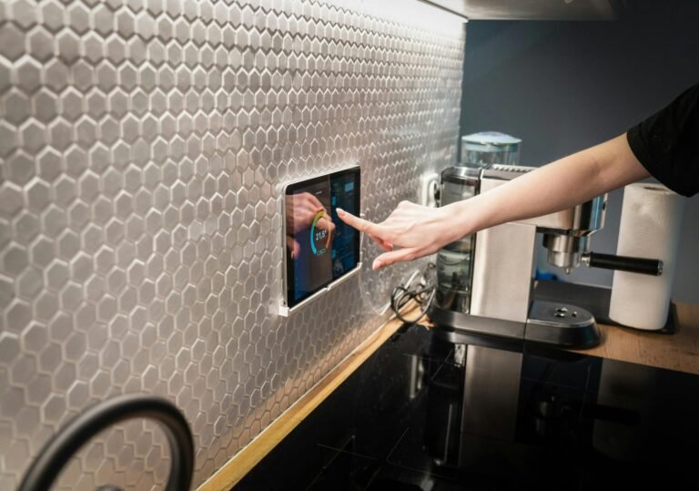 A modern kitchen with a touchscreen smart home control panel integrated into a hexagon-patterned wall.