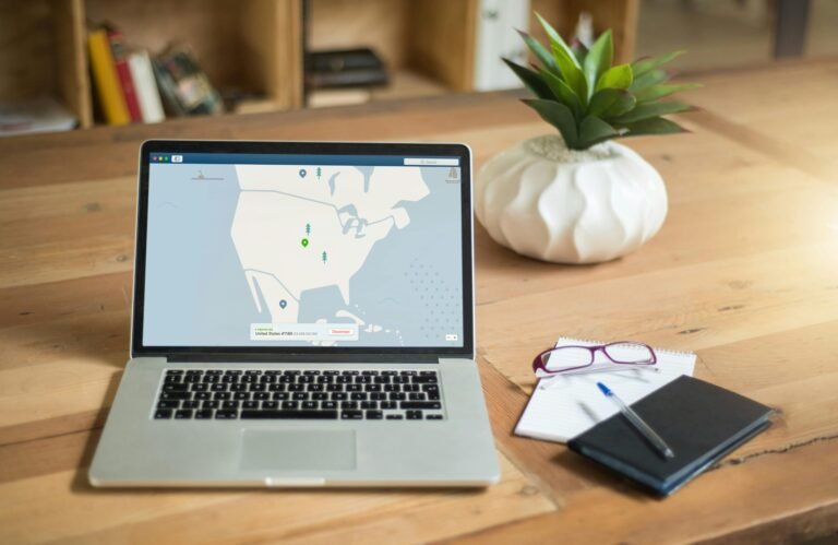 A laptop displaying VPN software sits on a wooden desk with a notepad and plant offering a secure workspace vibe.