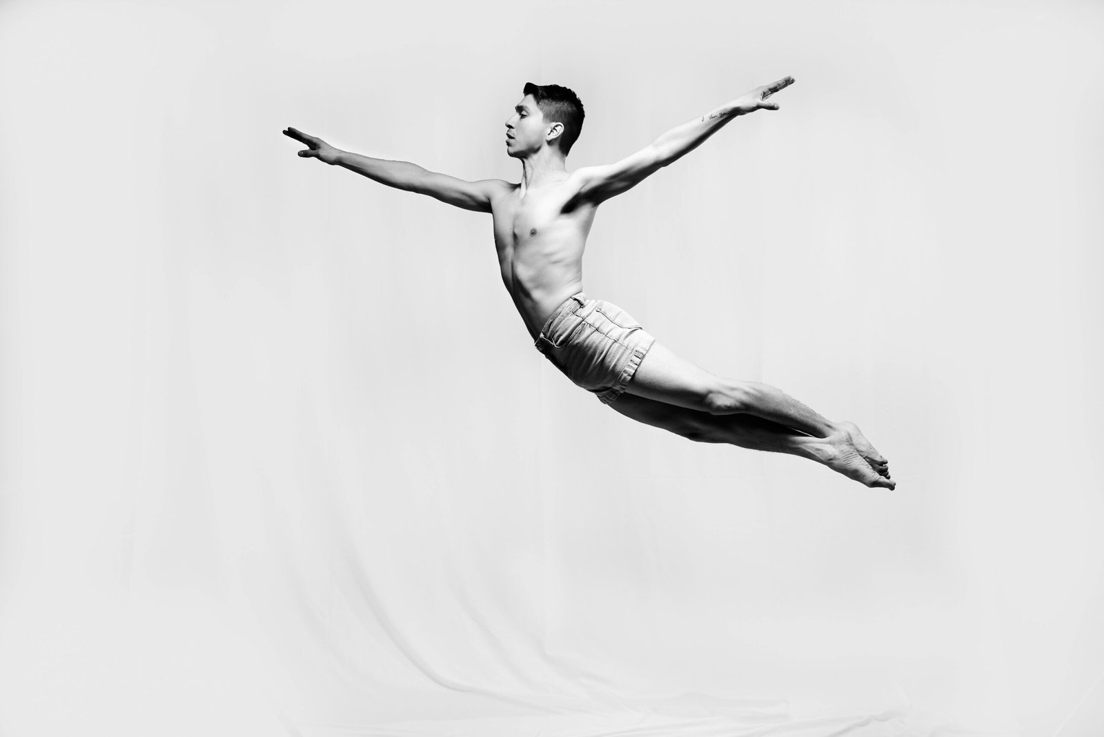 A captivating black and white photo of a male gymnast performing a dramatic leap, showcasing strength and grace.