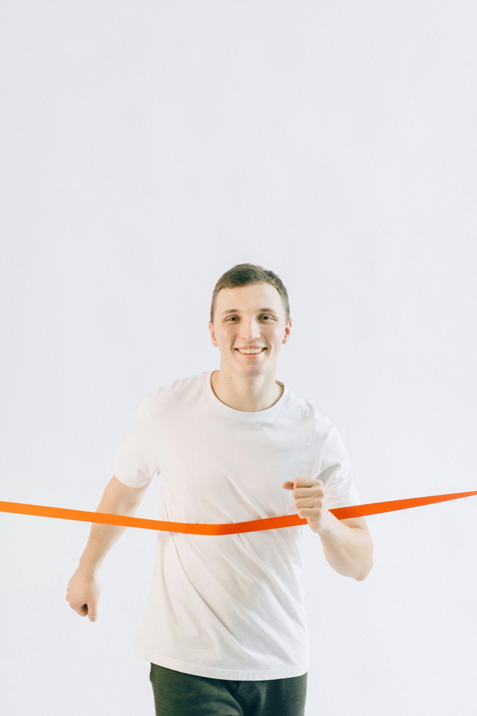 Joyful young male crossing the finish line with enthusiasm indoors.