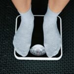 Top view of feet in socks standing on a bathroom scale, indicating weight measurement.