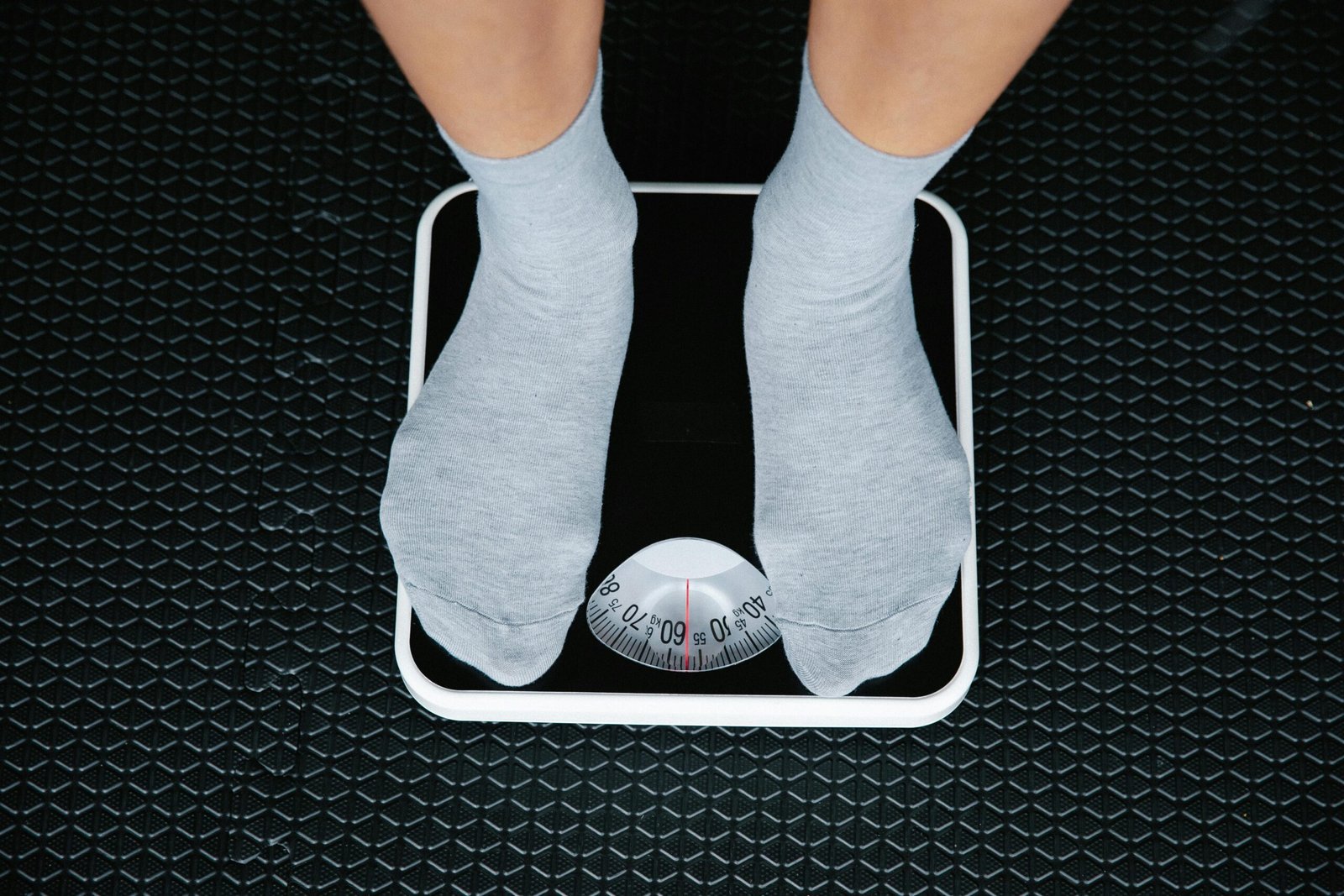 Top view of feet in socks standing on a bathroom scale, indicating weight measurement.