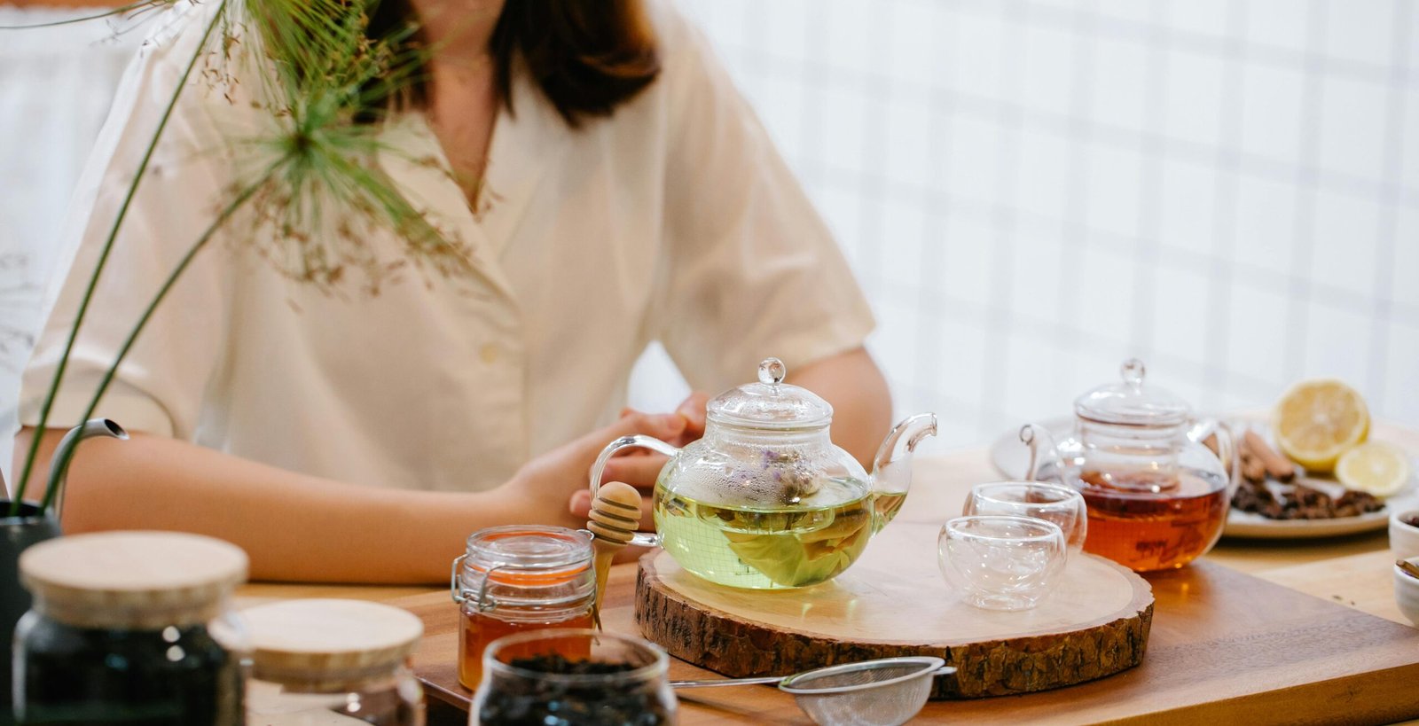 Woman enjoying a cozy tea time with herbal infusions and honey in a warm, inviting setting.